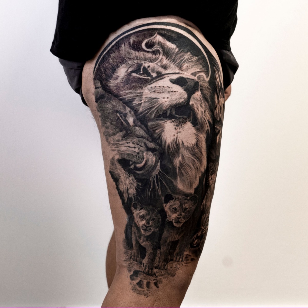 León con sus cachorros, realismo tatuado en el muslo