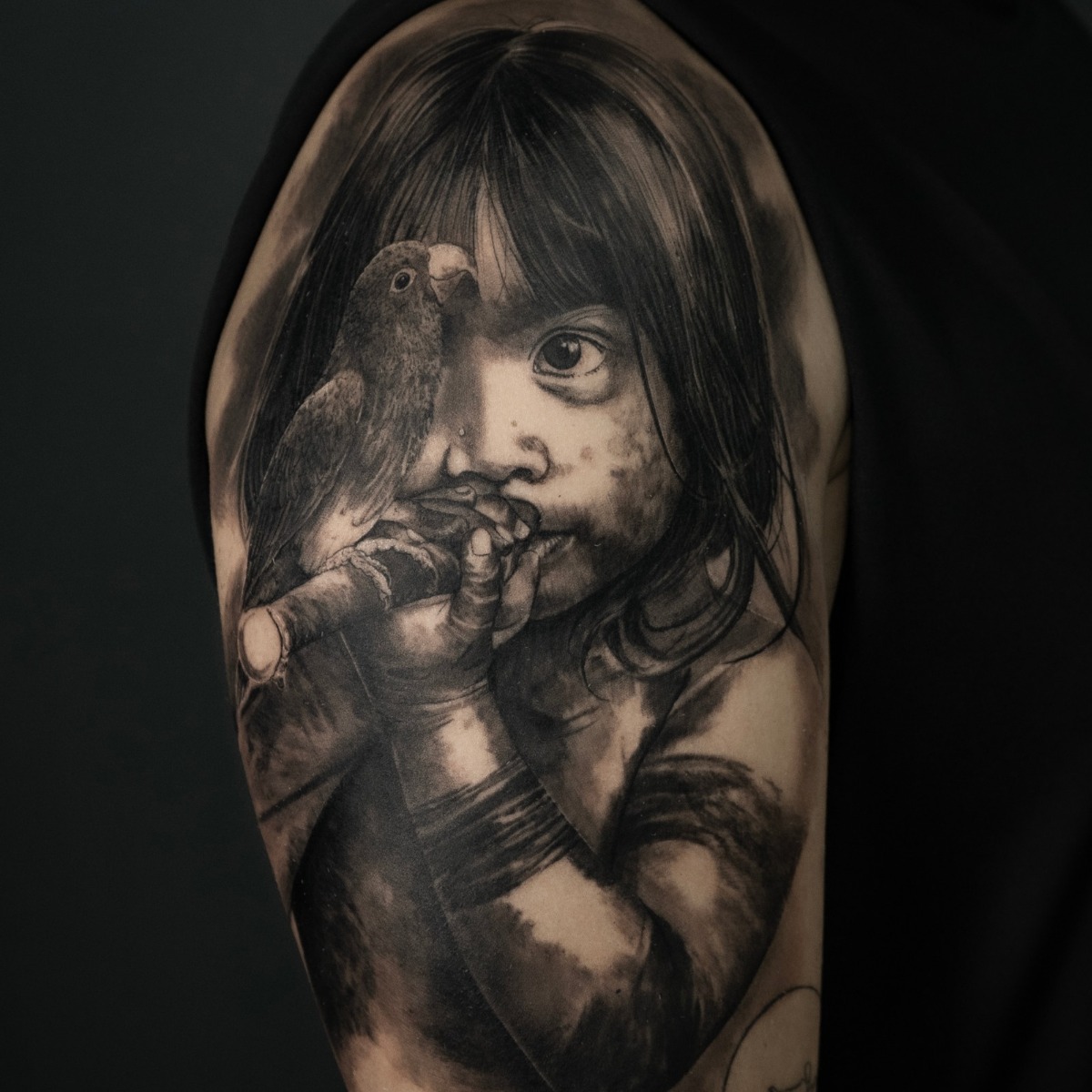 Retrato realista de una niña con un pájaro, tatuado en el brazo